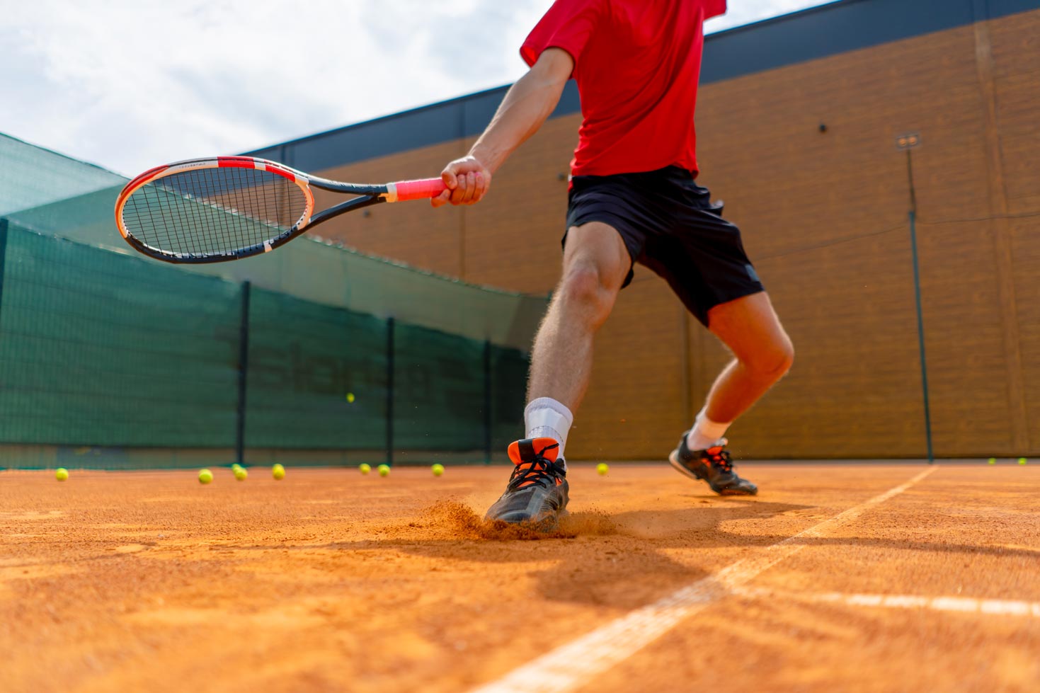 Un tennista scivola sulla terra rossa durante un'azione di gioco, a simboleggiare l'impegno e le sfide di equilibrio che gli studenti-atleti affrontano ogni giorno tra campo e studio.